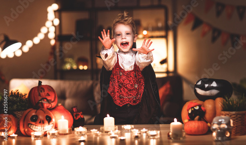 happy child boy in costumes of vampire in a dark house in halloween