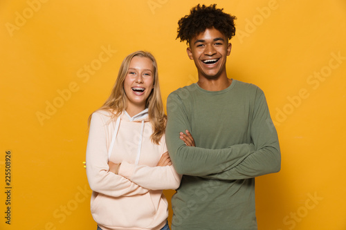 Photo of happy students man and woman 16-18 with dental braces laughing at camera, isolated over yellow background