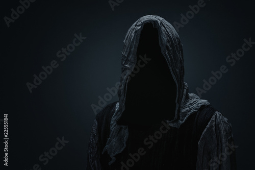 Silhouette of Grim Reaper over dark gray background with copy space