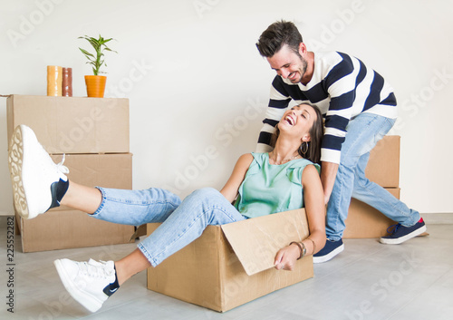 Happy couple in love having fun unboxing cardboards moving in the new house 