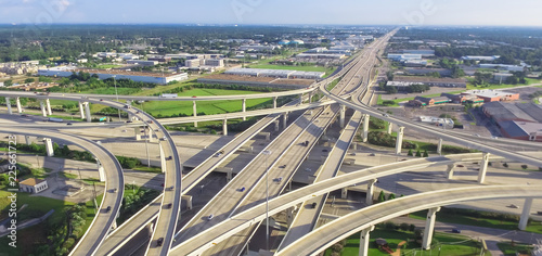 Panorama horizontal aerial view massive highway intersection, stack interchange blue sky in Houston, Texas, USA. Elevated road junction overpass, five-level freeway carry heavy rush hour traffic