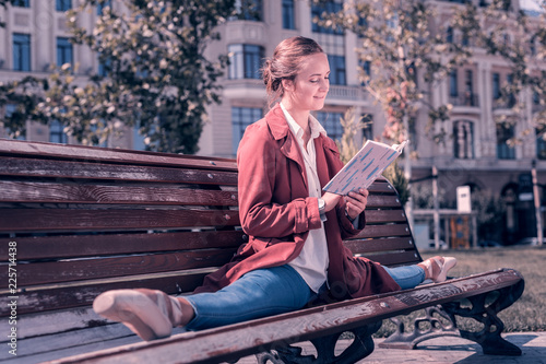 My hobby. Joyful positive ballerina holding a book while reading it in the park