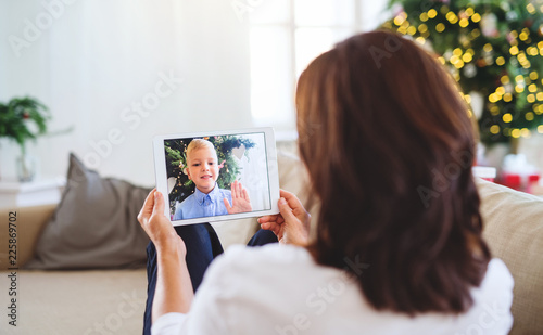 Senior woman with tablet talking with her grandson through online video phone call.