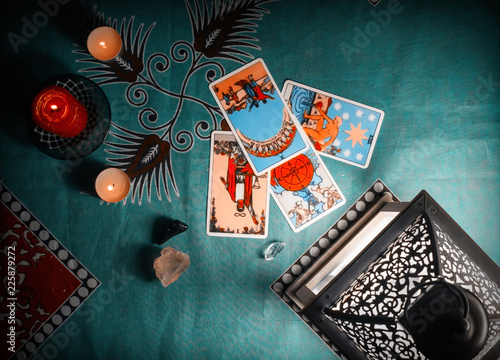 Fortune-telling on traditional tarot cards on a blue tablecloth with a lantern and candles.