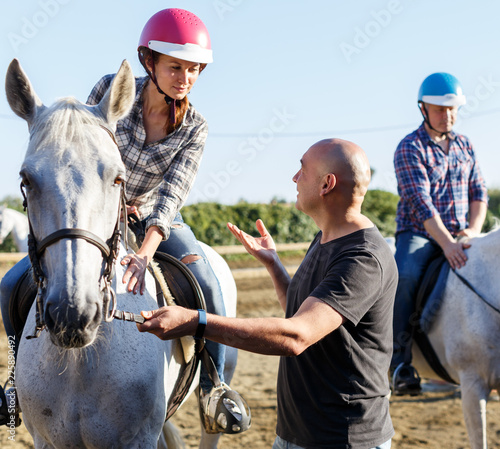 Trener mówi do kobiety podczas jazdy konnej na ranczo