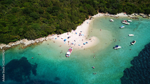 Aerial drone bird's eye view photo of iconic paradise sandy beach of blue lagoon with deep turquoise clear sea and pine trees in complex island of Mourtos in Sivota area, Epirus, Greece