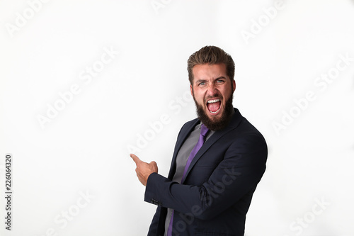 Attraktiver Geschäftsmann zeigt mit seinem Finger über seinen Schulter, auf einen weißen Hintergrund