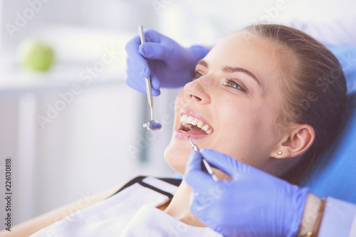 Young Female patient with open mouth examining dental inspection at dentist office.