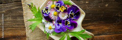 Fresh salad with smoked salmon, black olives, cherry tomatoes and edible flowers on wooden background.