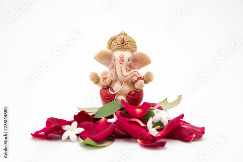 Lord Ganesha Idol with rose petals on white background, ganesh chaurthi, ganesh pooja