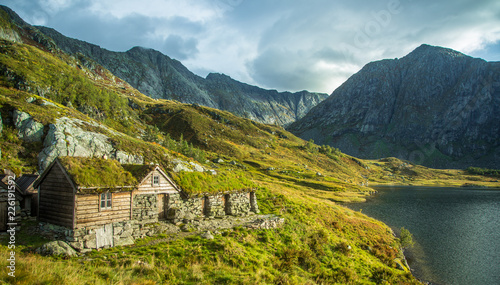 A beautiful, historic stone buildings in the mountains of Folgefonna National Park in Norway. Old houses with grass roofs near the lake. Autumn landscape.