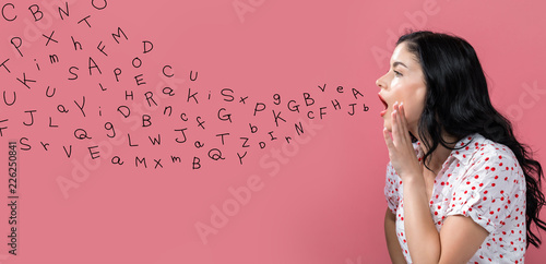 Alphabet letters with young woman speaking on a pink background