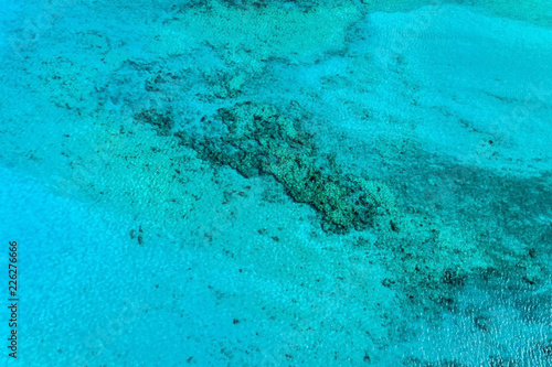 Top view of blue ocean water with reefs. Nature summer background