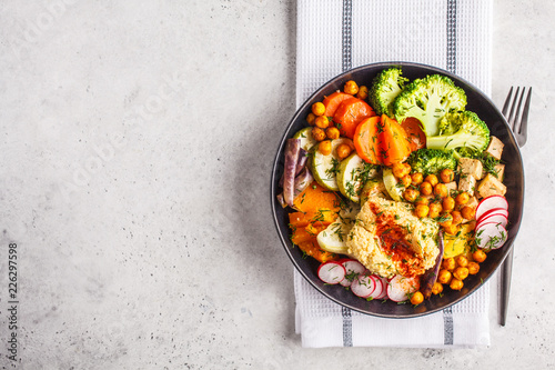 Vegan Buddha bowl with baked vegetables, chickpeas, hummus and tofu, top view.