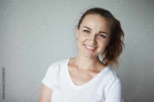 Cute young fairy-eyed girl smiling, looking at camera, on white background close-up.
