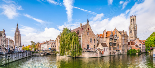 Panoramic city view with historical houses, church, Belfry tower and famous canal in Bruges, Belgium.