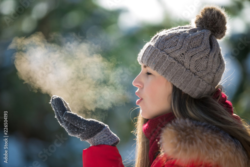 Attractive young woman breathe out steam outdoor in winter