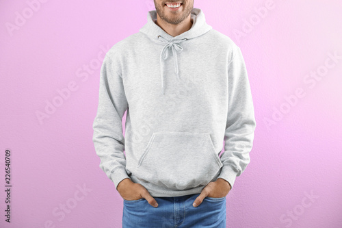 Man in hoodie sweater on color background. Space for design
