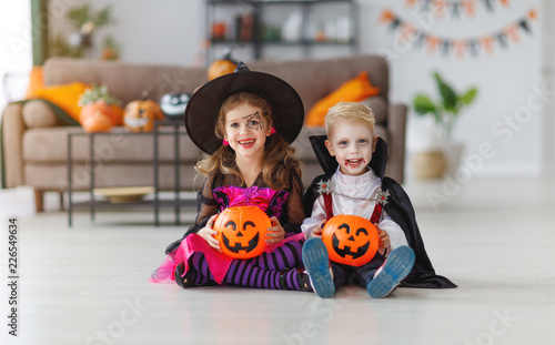 happy children in costumes of witch and vampire are preparing home for Halloween