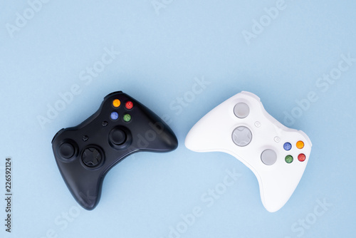 Two joysticks, black and white on a pastel blue background. White and black gamepad are isolated on a pastel blue background. Computer game competition. Gamer concept. Copyspace