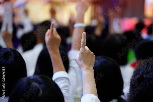 people reacting to the question by raising their index finger together as teamwork for unity and unanimous agreement and collaboration in the classroom