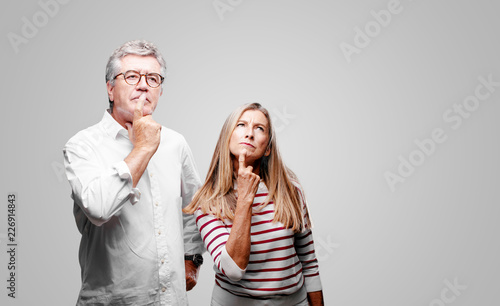 senior cool husband and wife With a confused and thoughtful look, looking sideways, thinking and wondering between different options.