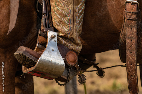 Lovely crafted stirrups and saddle, american cowboy warming up before rodeo performance on new ranch