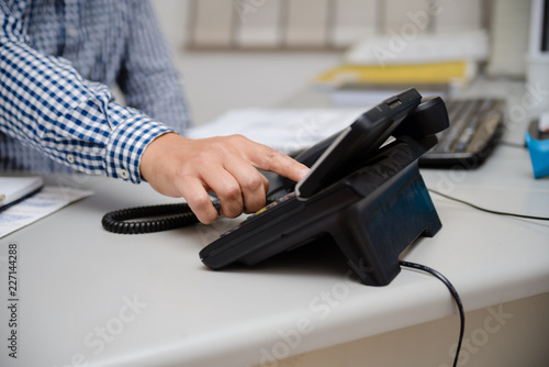 Close up of dialing a telephone device at office desk background, digital communication technology workplace. connection conference equipment group concept, happy professional telemarketer consulting