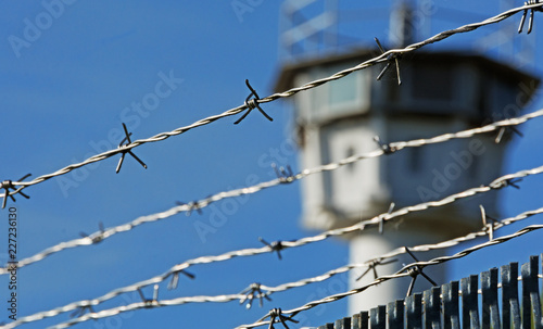 Stacheldraht mit Wachturm im Hintergrund