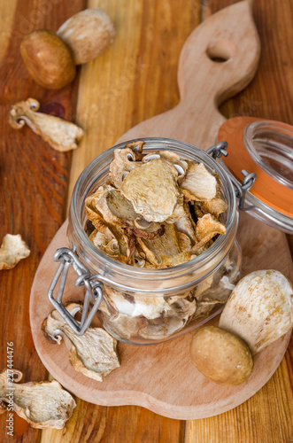 Dried forest mushrooms in a glass jar on a wooden background
