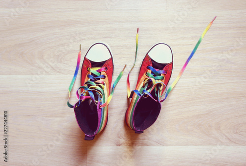 Sneakers LGBT colors. Fashionable shoes with untied shoelaces on wooden background. top view. 