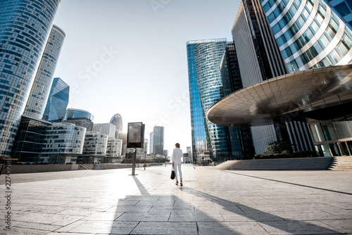 Business woman at the financial district with beautiful skyscrapers on the background during the morning light in Paris. Wide panoramic view