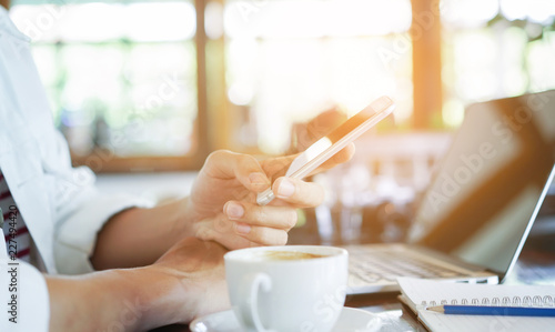 close up man hand holding smartphone and working at coffee shop