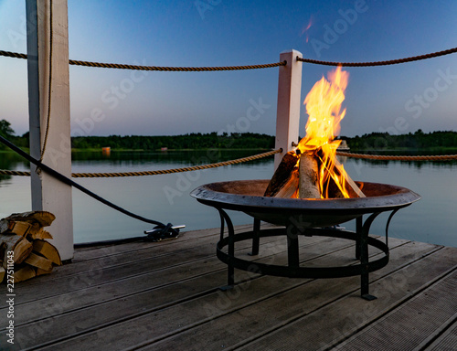 Feuer in einer Feuerschale am Abend am See