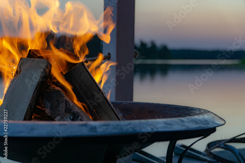 Flammen in einer Feuerschale in der Dämmerung am See