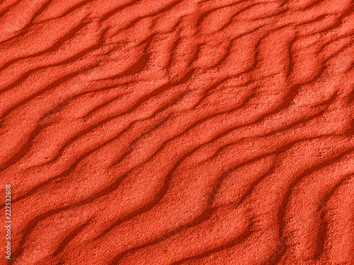 texture of red sand waves on the beach or in the desert. the ripples of the sand is diagonal.