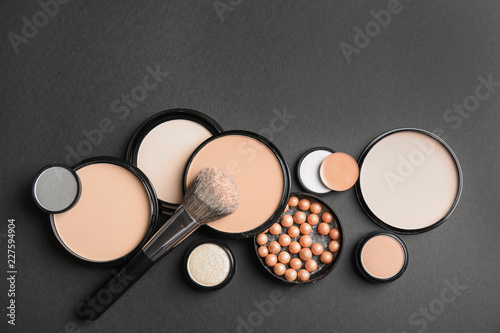 Flat lay composition with various makeup face powders on black background. Space for text