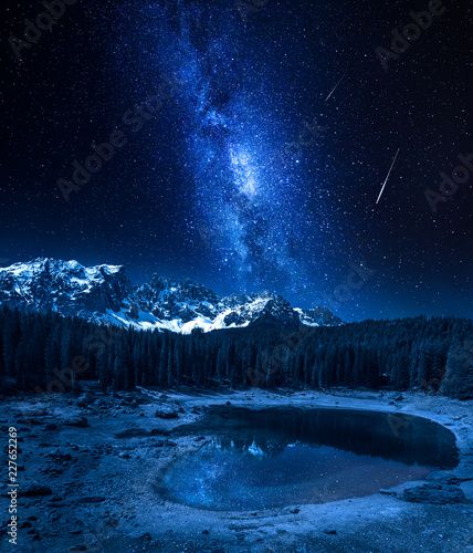 Milky way and falling stars over Carezza lake, Dolomites, Italy