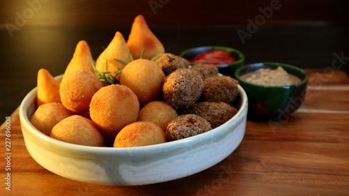 Traditional Brazilian snacks coxinha and quibe on wooden dark background. Selective focus.