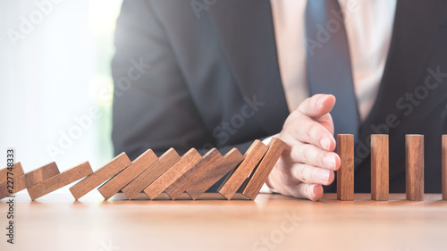 Problem Solving, Close up hand of businessman stopping risk falling blocks on table, Planning and strategy in business