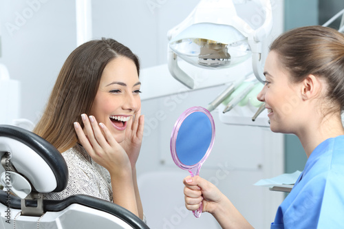 Szczęśliwy dentysty pacjent sprawdza wybielanie wynika