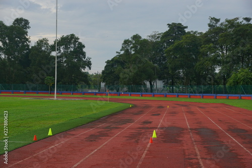 track and fields with 2 yellow cone on track with artificial grass inside a stadium