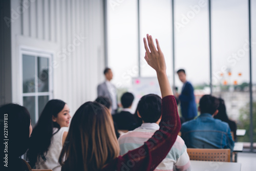 Woman raised up hands and arms in seminar class room to agree with speaker at conference seminar meeting room