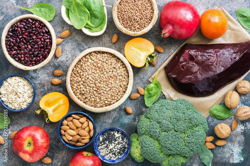 Foods high in iron. liver, broccoli, persimmon, apples, nuts, legumes, spinach, pomegranate. Top view, flat lay.