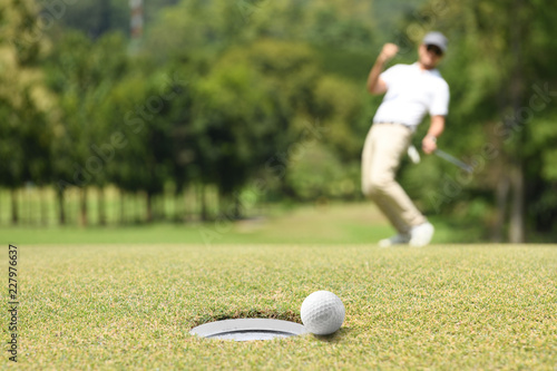 Man golfer cheering after a golf ball on a golf green