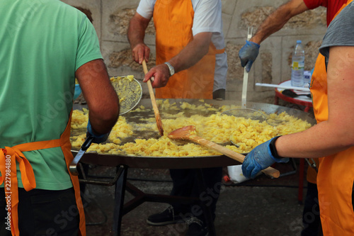 gente removiendo las patatas en una sartén gigante para preparar una tortilla española para una fiesta