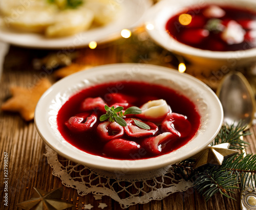 Christmas beetroot soup, borscht with small dumplings with mushroom filling in a ceramic bowl on a wooden table. Traditional Christmas eve dish in Poland. 