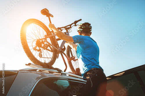 Mężczyzna rowerzysta górski zdjąć rower z dachu samochodu
