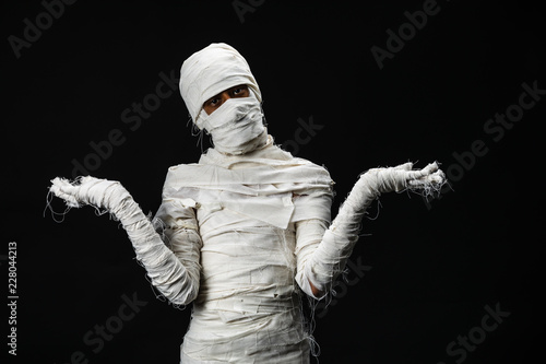 Studio shot portrait of young man in costume dressed as a halloween cosplay of scary mummy pose like a open hand acting on isolated black background