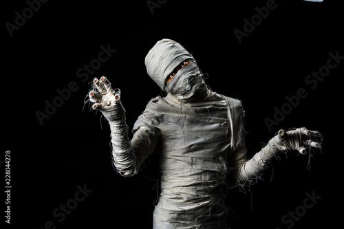 Studio shot portrait of young man in costume dressed as a halloween cosplay of scary mummy pose like a clamber acting on isolated black background